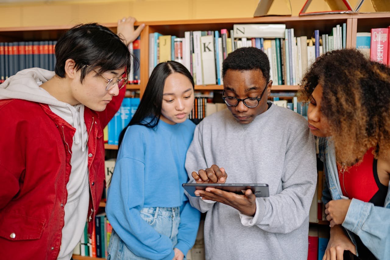 Students in a Library Looking at a Tablet Screen